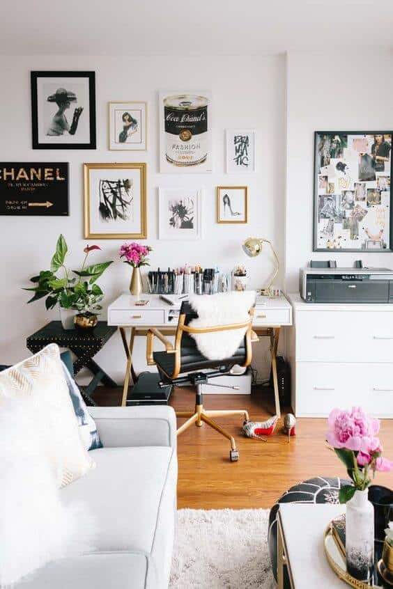 Bright living room office combo featuring a stylish white desk with a gold chair, gallery wall art, and natural light from large windows.