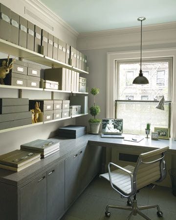 Sleek home office with L-shaped desk, built-in storage, and shelving for organization. Soft greys and greens create a calming workspace.