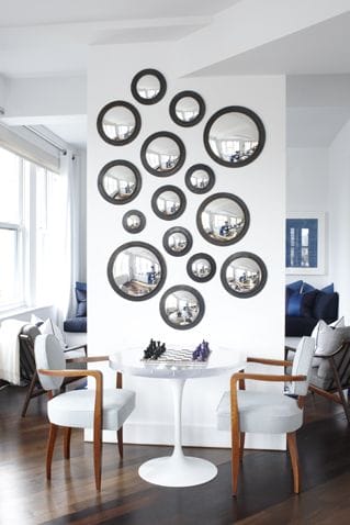 32 Mirror Decorating Ideas - Transform Home With Mirrors 12 Captivating arrangement of round mirrors on a white wall, enhancing light in a cozy living room with mid-century modern decor.