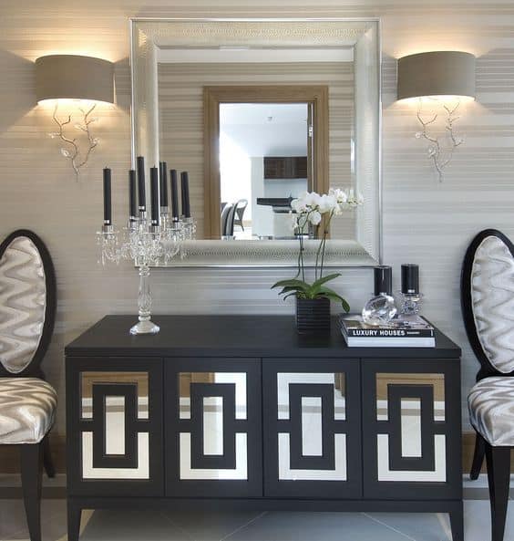 32 Mirror Decorating Ideas - Transform Home With Mirrors 13 Sleek black console table with mirrored panels, crystal candelabra, and a large mirror above, enhancing modern living room decor.