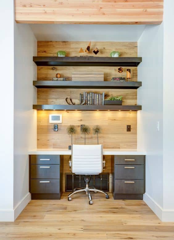 Compact home office with a 60-inch white desk and ergonomic chair, featuring floating shelves for storage and a light wood panel backdrop.