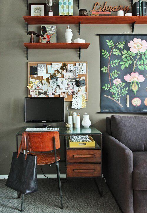 Sleek glass top desk with a wooden chair in a cozy living room office combo, featuring organized stationery and vibrant artwork.