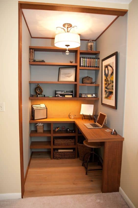 Compact home office nook with built-in wooden shelving and desk, light blue walls, and warm wood tones, maximizing a small space.