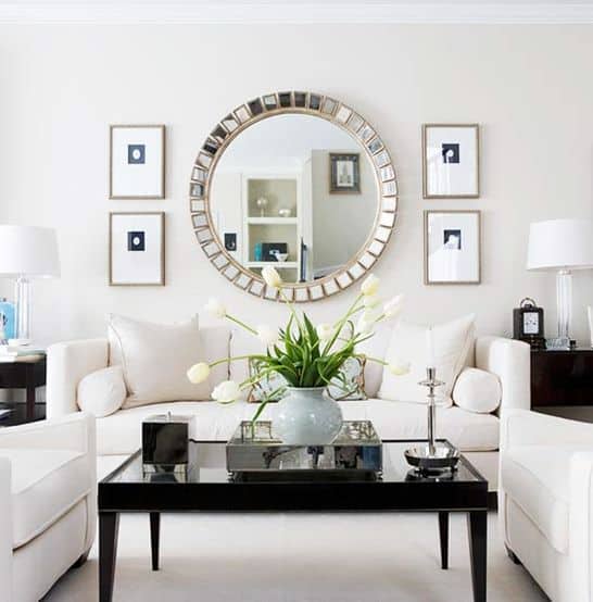 32 Mirror Decorating Ideas - Transform Home With Mirrors 20 Stylish living room featuring a round decorative mirror, white sofas, and a black glass coffee table, enhancing light and space.