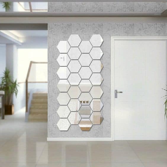 32 Mirror Decorating Ideas - Transform Home With Mirrors 21 Hexagonal decorative mirrors on a textured gray wall enhance light and space, complementing minimalist decor near a white door.