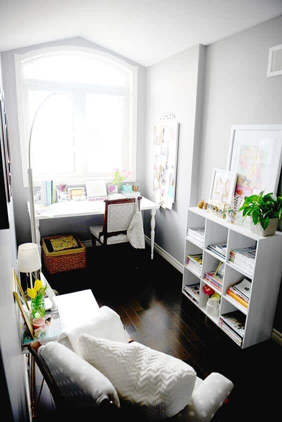 Bright home office with a large arched window, a 5-foot desk, patterned chair, and a cozy reading nook. Dark hardwood floor complements soft gray walls.