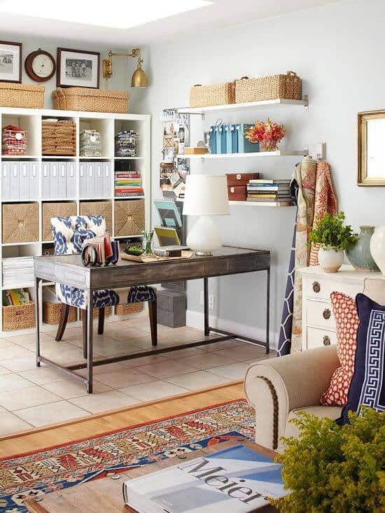 Sleek metal desk in a light blue-walled living room, paired with a chic chair, organized shelves, and vibrant textiles, creating a stylish workspace.