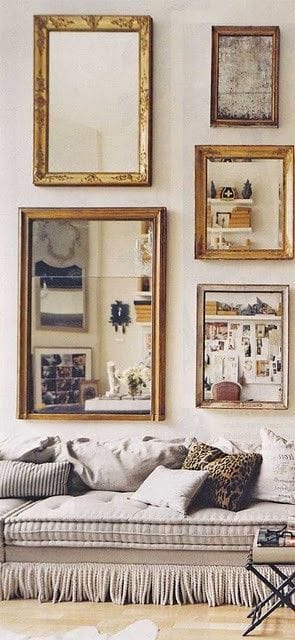 32 Mirror Decorating Ideas - Transform Home With Mirrors 4 Five framed artworks and mirrors above a light sofa create a stylish living room decor. The ornate gold mirror contrasts with vintage frames, enhancing the cozy vibe.