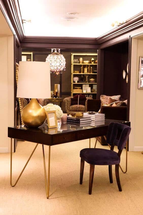 Sleek home office with a dark wood desk and gold legs, velvet chair, and chic animal print seating, creating a cozy living room office combo.