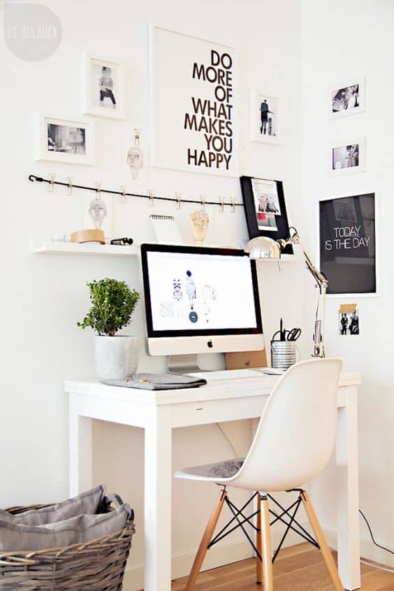 Sleek, minimalist home office with a white desk, ergonomic chair, large monitor, organized stationery, potted plant, and inspiring wall decor.