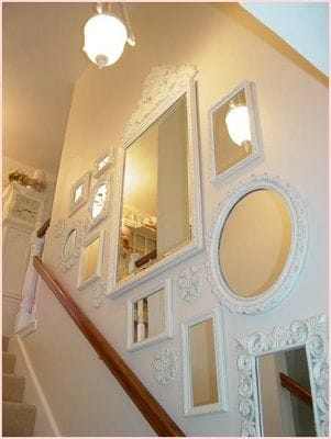 32 Mirror Decorating Ideas - Transform Home With Mirrors 28 Curated arrangement of white-framed mirrors in various shapes and sizes on a light wall, enhancing elegance and brightness in the space.