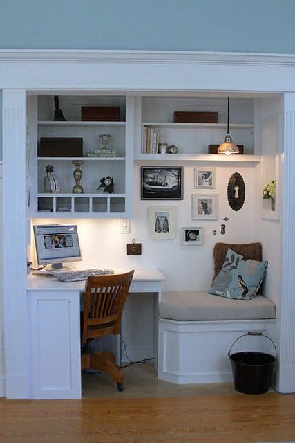 Home office with a built-in desk, white cabinetry, and a wooden chair. Features open shelving, a cozy nook, and soft blue walls for a tranquil workspace.