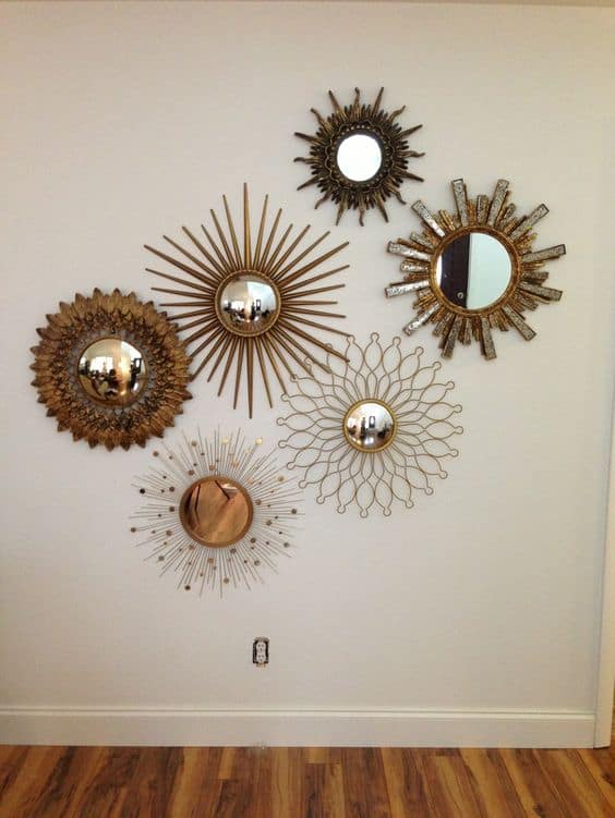 32 Mirror Decorating Ideas - Transform Home With Mirrors 29 Stylish arrangement of six decorative sunburst mirrors in metallic frames, enhancing a neutral wall and hardwood flooring.