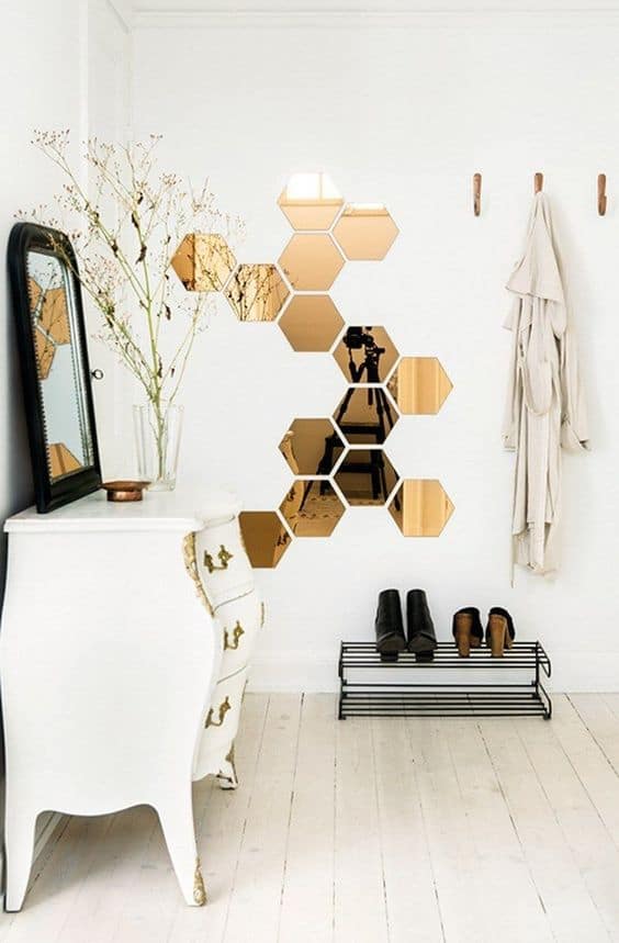 32 Mirror Decorating Ideas - Transform Home With Mirrors 5 Striking arrangement of hexagonal mirrors in a metallic finish on a white wall, complemented by a chic dresser and minimalist decor.