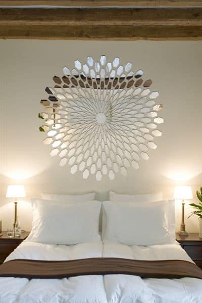 32 Mirror Decorating Ideas - Transform Home With Mirrors 30 Round sunburst mirror above a bed with white linens and a brown headboard. Symmetrical layout with bedside lamps enhances modern decor.