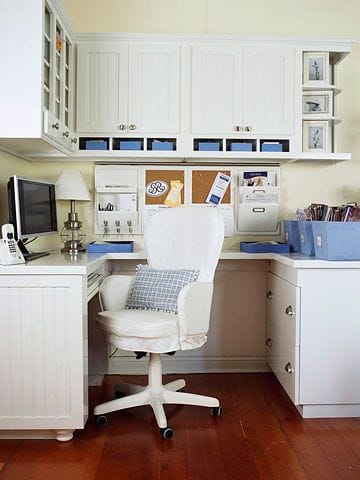 Compact home office with wall-mounted cabinetry and a 5x2.5 ft desk. Features blue storage bins and a bulletin board, maximizing productivity.