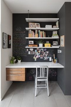 Sleek home office with a white desk, wooden chair, and a black chalkboard wall; open shelving maximizes vertical space in this compact setup.
