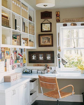 Compact home office features a white built-in shelf, light desk, stylish chair, and natural light from a large window, perfect for productivity.