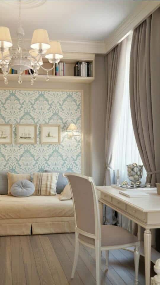 Serene living room office combo features a beige daybed, classic white desk, and stylish chandelier, enhancing functionality and aesthetics.