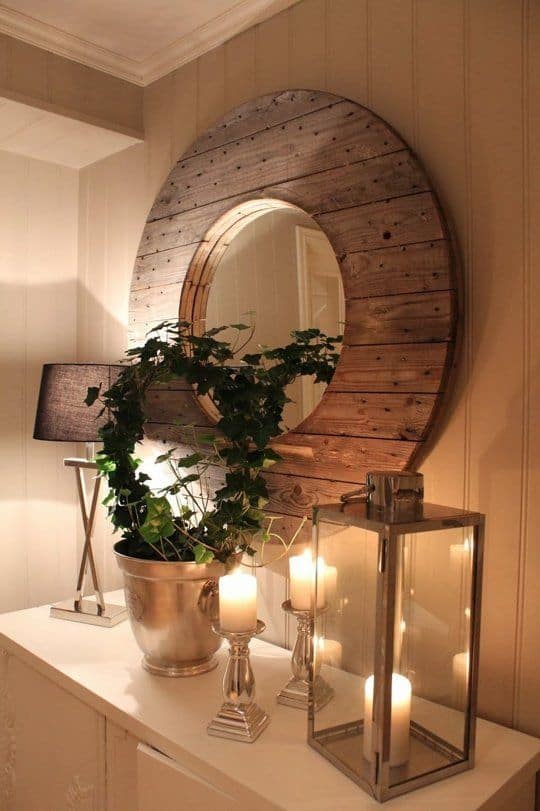 32 Mirror Decorating Ideas - Transform Home With Mirrors 9 Rustic mirror decor with a large oval mirror framed in reclaimed wood, above a white console table, surrounded by ivy and silver candle holders.