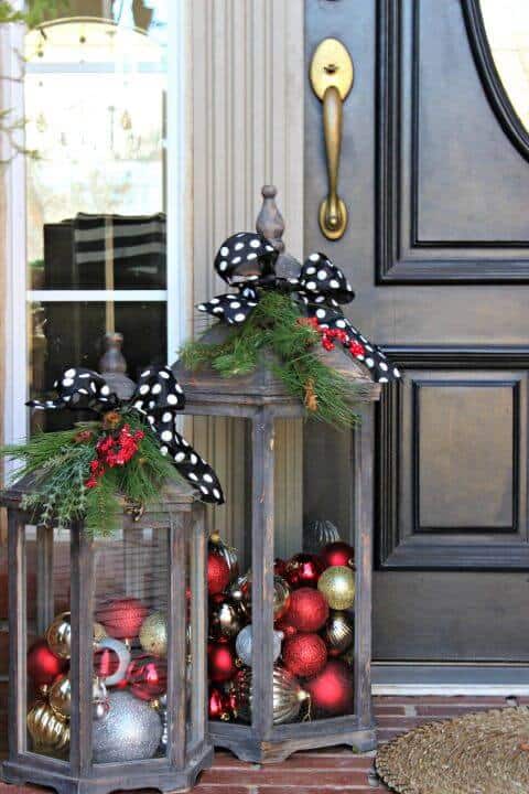 Two rustic wooden lanterns, about 30 inches tall, feature greenery and polka dot bows, showcasing shiny red and gold Christmas ornaments.