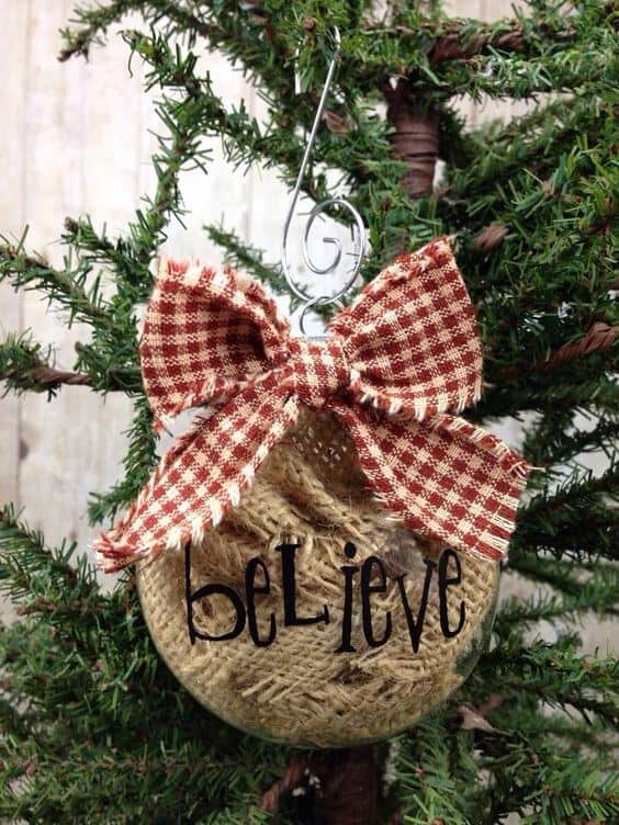 37 DIY Christmas Ornament Ideas For You Unique Decor 3 Clear glass Christmas ornament filled with burlap, adorned with a red and white checked ribbon, featuring 'believe' lettering for a rustic touch.
