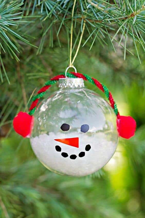 37 DIY Christmas Ornament Ideas For You Unique Decor 22 Transparent glass Christmas ornament featuring a snowman face with a carrot nose, adorned with red pom-poms and strung with pipe cleaner.