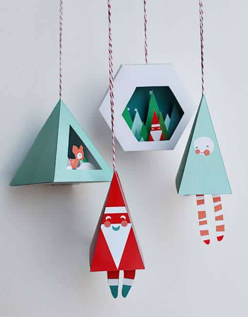 37 DIY Christmas Ornament Ideas For You Unique Decor 31 Red Santa figure, teal triangular tree, and hexagon with winter scene suspended from ceiling. Perfect for DIY Christmas ornaments and festive decor.