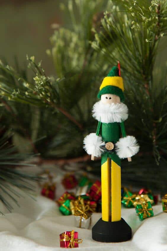 37 DIY Christmas Ornament Ideas For You Unique Decor 34 Handcrafted wooden elf figurine, 10 inches tall, in green and yellow with faux fur accents, surrounded by pine branches and gifts, perfect for DIY Christmas ornaments.
