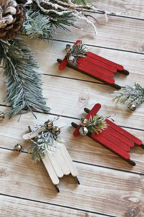37 DIY Christmas Ornament Ideas For You Unique Decor 37 Three small sleds made from popsicle sticks, painted red and white, adorned with faux evergreen leaves and jingle bells.
