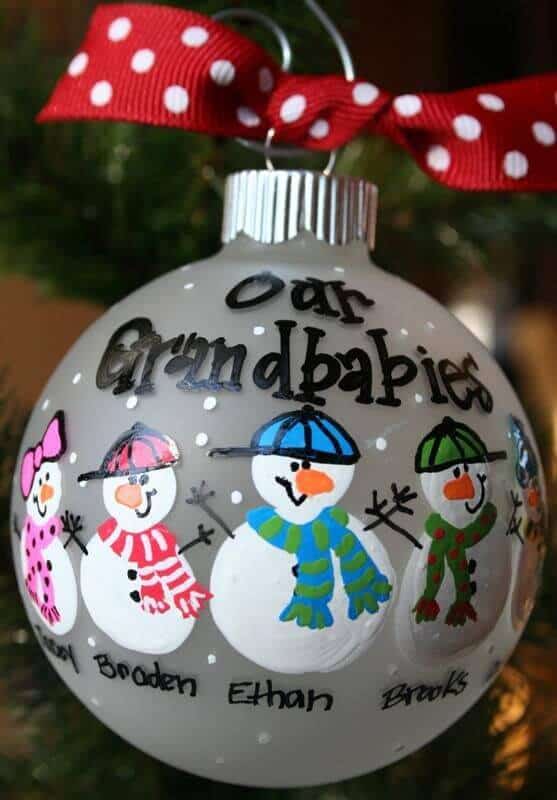 37 DIY Christmas Ornament Ideas For You Unique Decor 6 Custom ornament with a frosted glass sphere, hand-painted snowmen in colorful scarves, and names inscribed. Finished with polka-dotted ribbon.