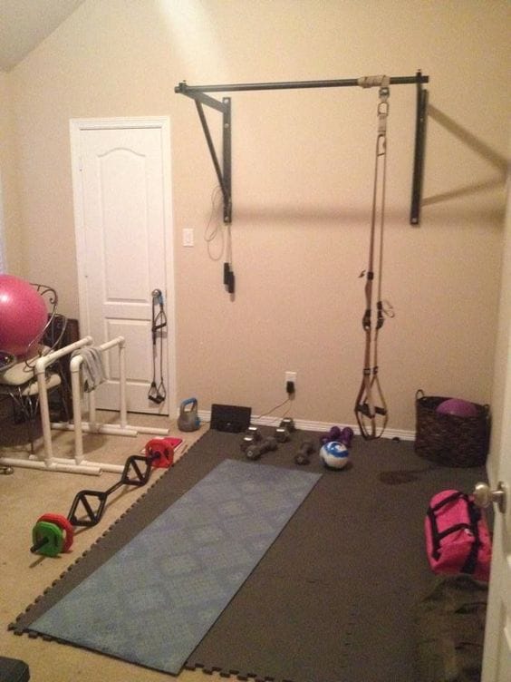 36 Home Gym Ideas - Layouts For Your Perfect Workout Spot 15 Home gym featuring rubber flooring, wall-mounted pulley system, free weights, and a stability ball in a neutral-toned space.