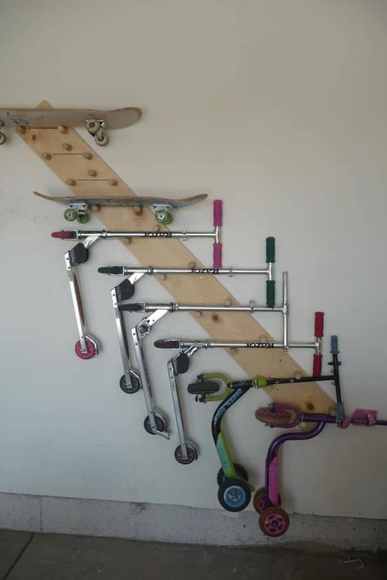 Vertical wooden board with hooks for scooters, maximizing garage space and promoting organized storage solutions.
