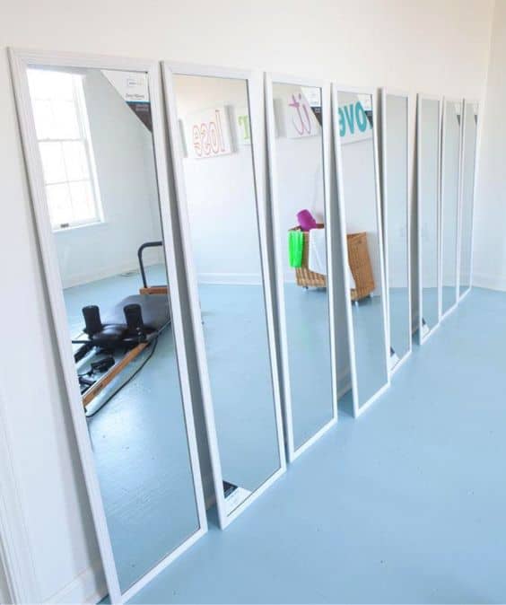 36 Home Gym Ideas - Layouts For Your Perfect Workout Spot 18 Seven tall, rectangular mirrors with slim white borders line a white wall, enhancing a bright, open atmosphere in a minimalist home gym.