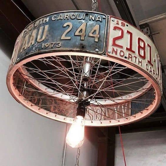 Repurposed vintage license plates form a unique chandelier, featuring a circular frame and exposed Edison bulb, ideal for rustic garage decor.