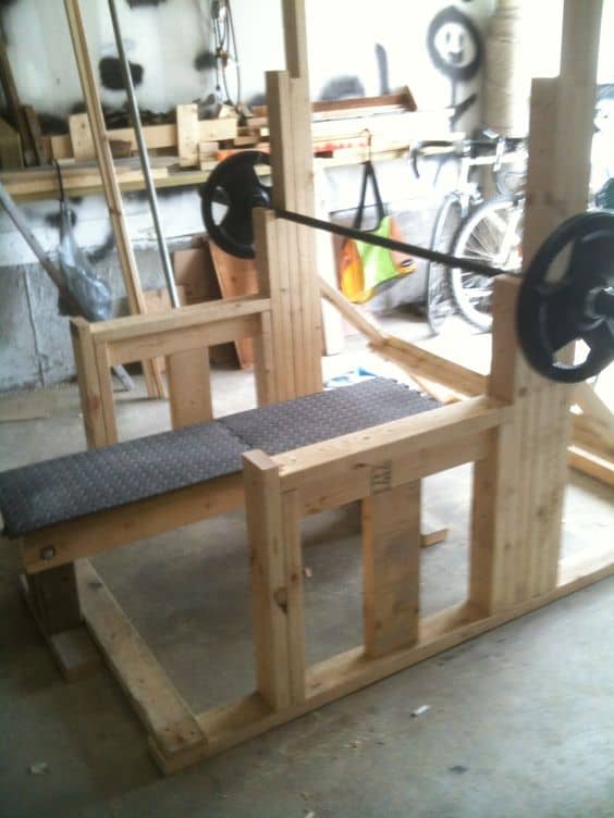36 Home Gym Ideas - Layouts For Your Perfect Workout Spot 31 Sturdy wooden bench press setup in a garage, featuring vertical support beams and a padded surface, ideal for home workouts.