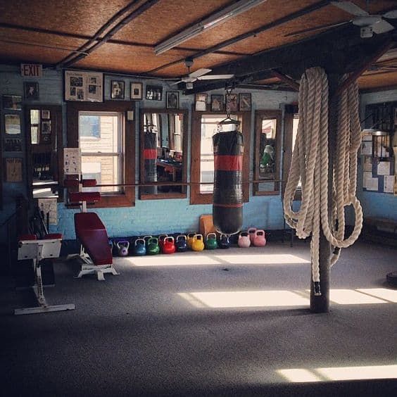 36 Home Gym Ideas - Layouts For Your Perfect Workout Spot 32 Spacious home gym features exposed wooden beams and high ceilings. Natural light, colorful kettlebells, mirrors, and a boxing bag enhance functionality.