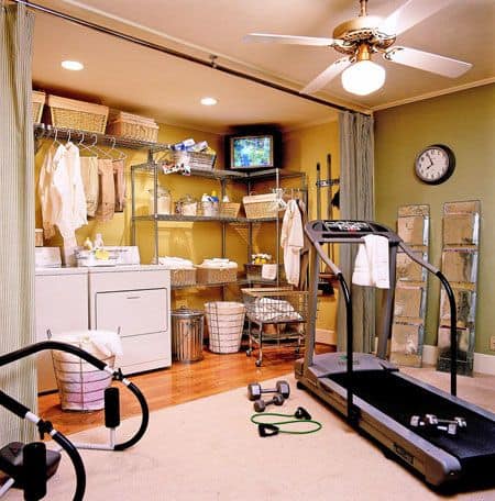 36 Home Gym Ideas - Layouts For Your Perfect Workout Spot 37 Home gym laundry room with treadmill and laundry appliances, featuring a light green palette and organized shelving for equipment.