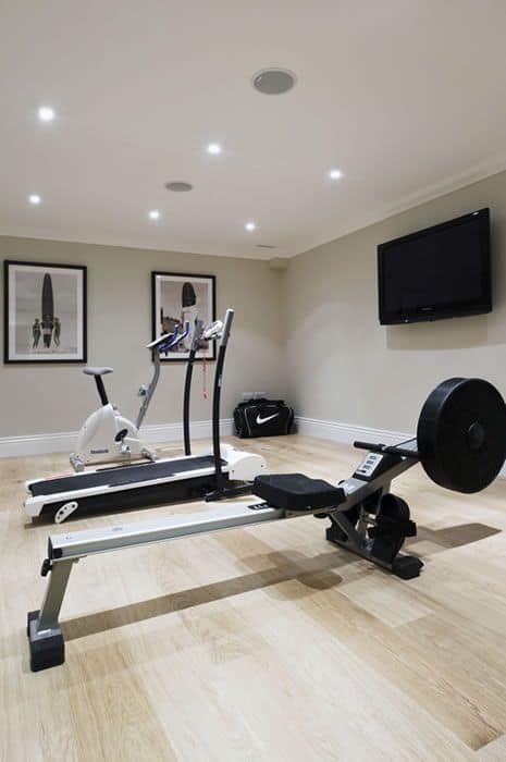 36 Home Gym Ideas - Layouts For Your Perfect Workout Spot 6 Well-organized home gym featuring a rower, elliptical, and weights in a 12x10 space with warm wood flooring and gray walls.