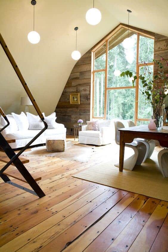 Spacious farmhouse interior featuring warm pine flooring, rustic wooden accents, white sofas, and a cozy ambiance with modern lighting.