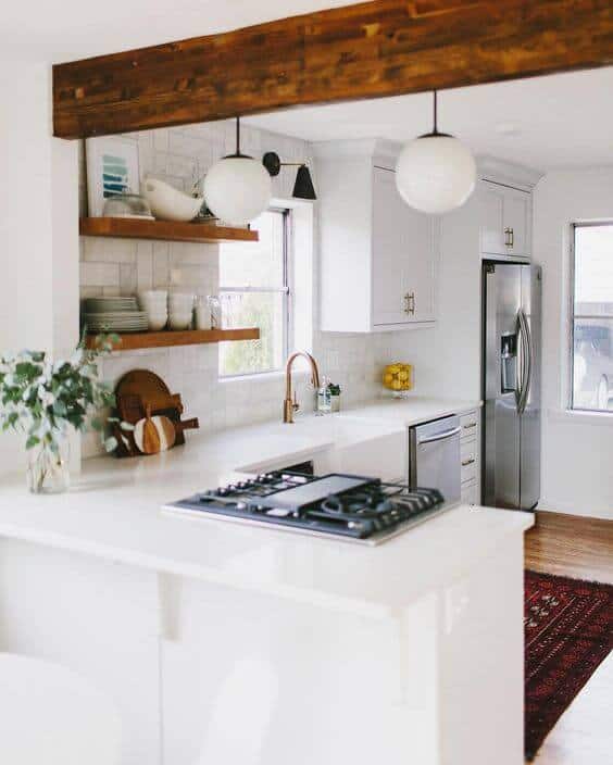 Modern small kitchen with white cabinetry, quartz island, built-in gas cooktop, and natural light from large windows.