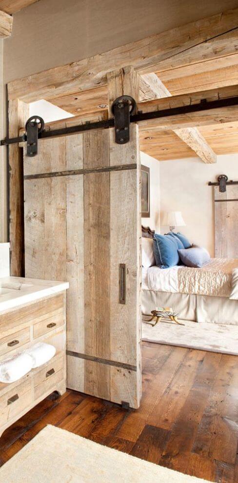 Rustic bathroom design with reclaimed wood sliding doors, weathered wood cabinetry, double vanity, and a cozy, farmhouse aesthetic.