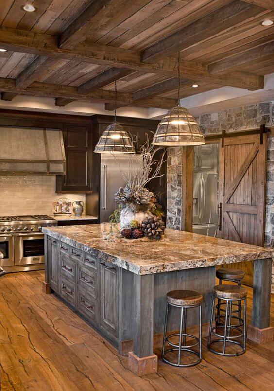 Rustic kitchen with a large granite island, dark wood base, exposed beam ceiling, industrial pendant lights, and stone backsplash.