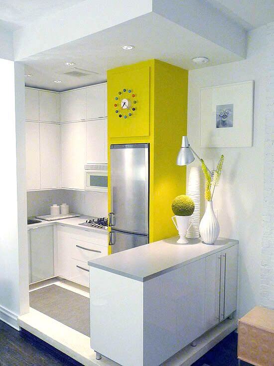 Compact kitchen with white cabinetry, a bold yellow accent wall, stainless steel refrigerator, and modern 8-foot countertop with gas stovetop.