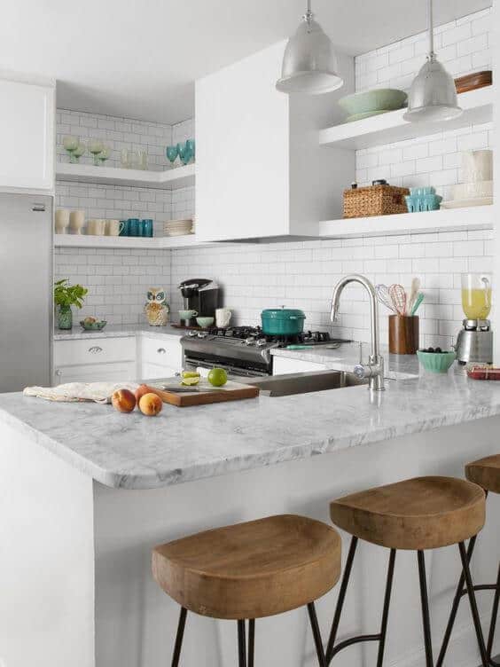 Modern small kitchen with white cabinetry, subway tile backsplash, and a marble-topped island. Features energy-efficient appliances and open shelving.