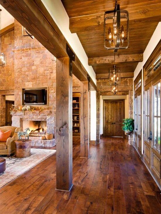 Modern rustic interior featuring exposed wooden beams, stone walls, and natural light. Cozy open-concept living area with lantern-style lighting.