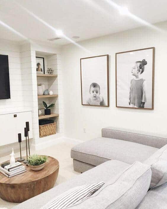 Bright basement playroom with soft gray sectional sofa, round wooden coffee table, and decorative shelves, perfect for kids' activities.