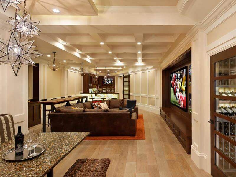 Contemporary basement playroom features a cozy lounge feel with a long granite countertop, sectional sofa, and vibrant area rug, ideal for kids' activities.