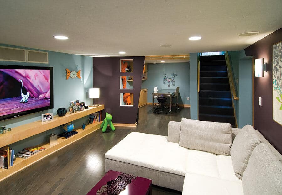 Sleek basement playroom with a large sectional sofa, colorful decor, and natural light, perfect for kids' activities and fun.