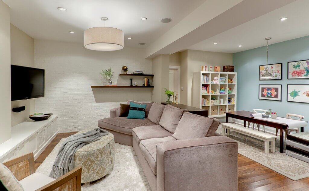 Spacious basement playroom with bright decor, featuring a soft rug, play area, and storage, perfect for kids' activities and games.